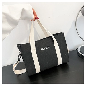 Détail du sac cabas en toile noire montrant l'imprimé FASHION et les anses blanches
