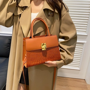 Fashionable caramel faux crocodile leather crossbody bag with gold buckle on a model