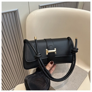 Close-up of black leather handbag with gold metal clasp and woven knot strap detail