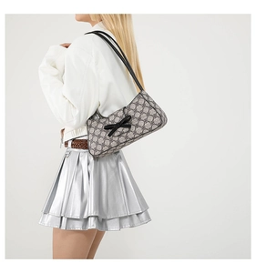 Model trägt eine Retro-Halbmond-Schultertasche mit Monogramm und Schleifen-Detail