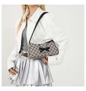 Detail der Vintage-Schultertasche mit Monogramm, Lederschleife und Riemen am Model