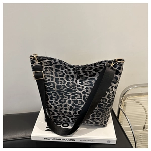 Detail of leopard print tote bag featuring black wide fabric strap and gold metal buckles