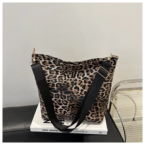 Detail of leopard print crossbody bag featuring black strap and gold metal hardware