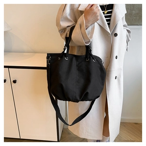 Detailed view of black canvas tote bag with metal grommets and shoulder strap