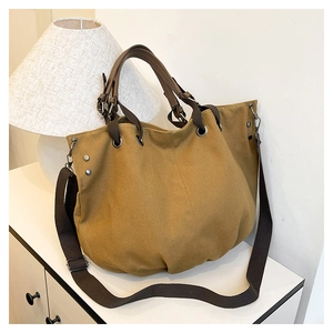 Close-up of khaki canvas tote bag featuring reinforced leather handles and silver hardware