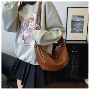 Macro detail of brown hobo bag showing textured soft leather and silver adjustable buckle