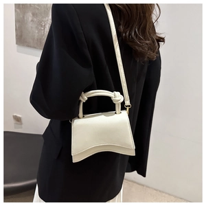 Detail of white hourglass crossbody bag with curved base and knotted handle on model