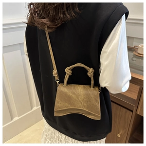 Detail of khaki leather bag with unique curved base and knotted handle on shoulder