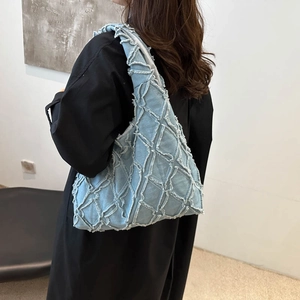 Sac fourre-tout en denim bleu clair avec texture diamant effilochée porté par un modèle