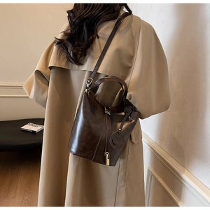 Détail d'un sac seau vintage marron foncé avec pendentif smiley et serrure métallique