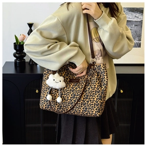 Close-up of leopard print canvas tote bag featuring brown leather straps and cloud charm