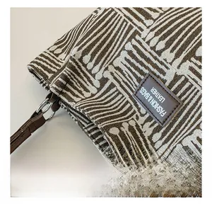 Close-up of geometric striped canvas fabric with leather logo tag and silver hardware