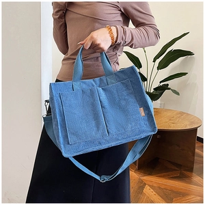 Dettaglio della borsa tote in velluto a coste blu con doppi manici e toppa in pelle fashion