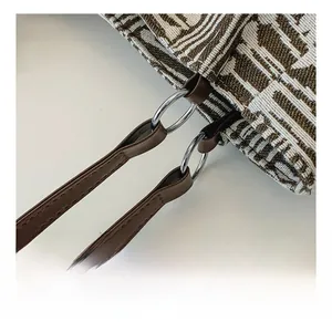 Close-up of durable silver metal rings and brown leather strap on jacquard tote bag