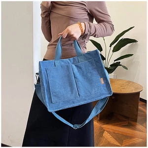 Dettaglio della borsa tote in velluto a coste blu con tasche frontali e tracolla regolabile