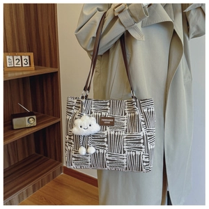 Detail of cream canvas tote bag with black geometric patterns and leather straps