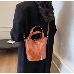 Sac seau vintage marron caramel avec breloque smiley et serrure dorée sur modèle