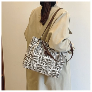 Detail of a large canvas tote bag with brown geometric patterns and leather straps