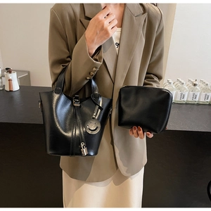 Détail d'un sac seau en cuir noir avec breloque cadenas en métal et petit sac assorti