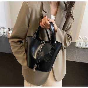 Détail du sac seau en cuir noir brillant avec pendentif serrure dorée et breloque sourire