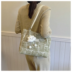 Detail view of large green geometric tote bag with white straps and cloud charm