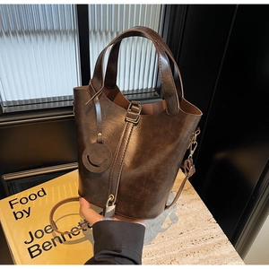 Gros plan d'un sac seau marron vintage avec pendentif smiley et détail de serrure