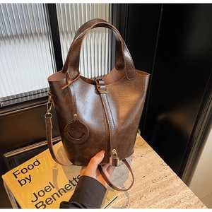 Détail du sac seau vintage en cuir huilé marron avec poignée et breloque cadenas latéral