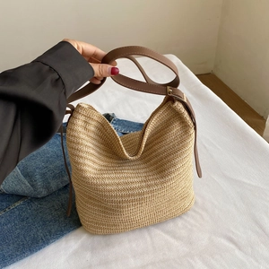 Detailed close-up of woven straw texture and adjustable brown leather shoulder strap