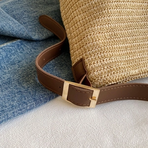 Close-up of woven straw texture and premium brown leather strap with golden buckle