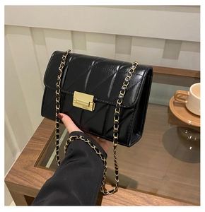 Détail d'un sac bandoulière matelassé noir avec chaîne dorée et fermoir métallique