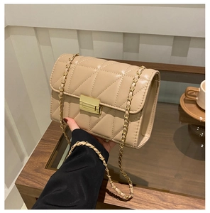 Gros plan du sac beige matelassé avec fermoir tournant doré et bandoulière chaîne
