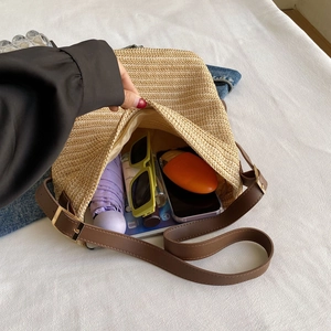 Detail of spacious straw crossbody bag interior holding daily essentials and gadgets