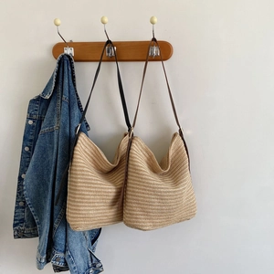 Detail view of large straw hobo bags with woven texture and thin leather straps