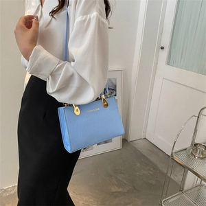 Light blue square crossbody bag with gold fashion lettering and metal handles