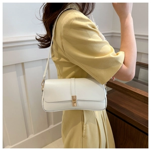 Détail du sac baguette en cuir blanc avec boucle en métal doré et coutures raffinées