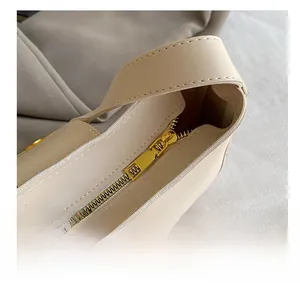 Close-up of golden metal zipper and smooth stitching on cream leather shoulder bag