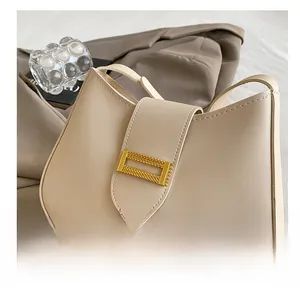 Detailed close-up of a beige faux leather hobo bag featuring a decorative gold metal buckle