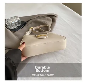 Detailed view of the wear-resistant bottom on this minimalist cream leather shoulder bag