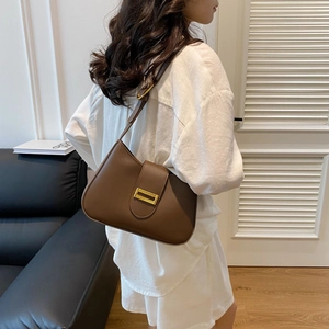 Detail of a brown leather shoulder bag featuring a rectangular gold metal buckle closure