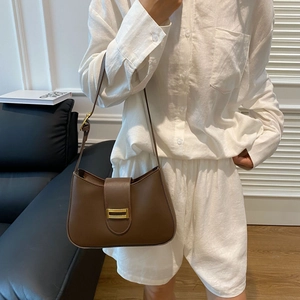 Detailed view of dark brown leather hobo bag with elegant gold buckle on white shirt