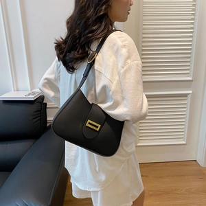 Detail of minimalist black underarm bag with sleek leather texture and gold buckle hardware