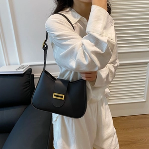 Black leather hobo bag with gold metal buckle shown on model in white shirt