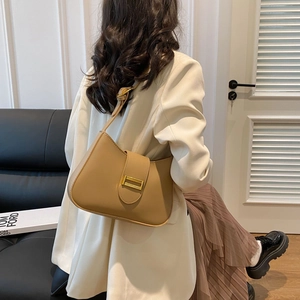 Light brown PU leather shoulder bag with gold buckle shown on a model in a modern office set