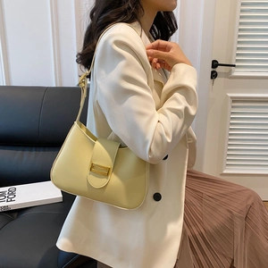 Side view of a creamy yellow macaron-style shoulder bag with elegant gold buckle hardware