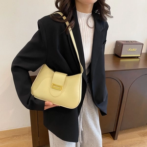 Detail showing smooth light yellow leather shoulder bag with elegant gold metal clasp