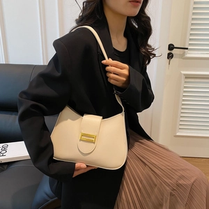 Detail of off-white leather shoulder bag with gold metal buckle shown on a model