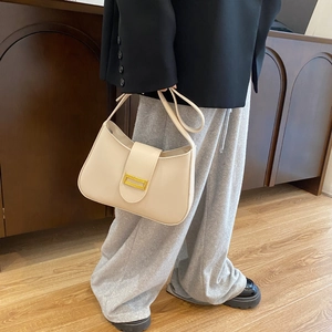 Close-up of beige moon bag with gold metal buckle and smooth faux leather texture