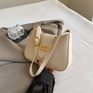 Detail of cream shoulder bag with gold hardware ring and smooth matte leather texture