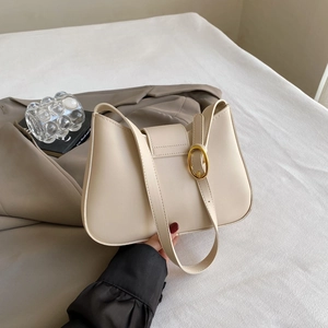 Detailed macro view of cream-colored faux leather hobo bag with gold metal buckle decoration