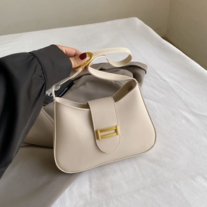 Detail of a minimalist beige shoulder bag featuring a sleek gold rectangular buckle closure